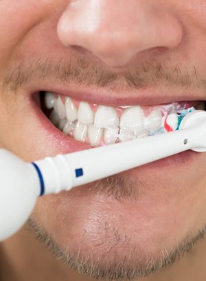 close up of a man using an electric toothbrush 