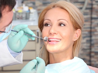 A middle-aged woman having her teeth checked by her dentist