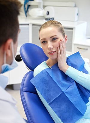 woman holding jaw while talking to dentist