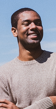man in tan sweater smiling