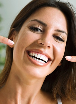 Smiling woman pointing to her white, straight teeth
