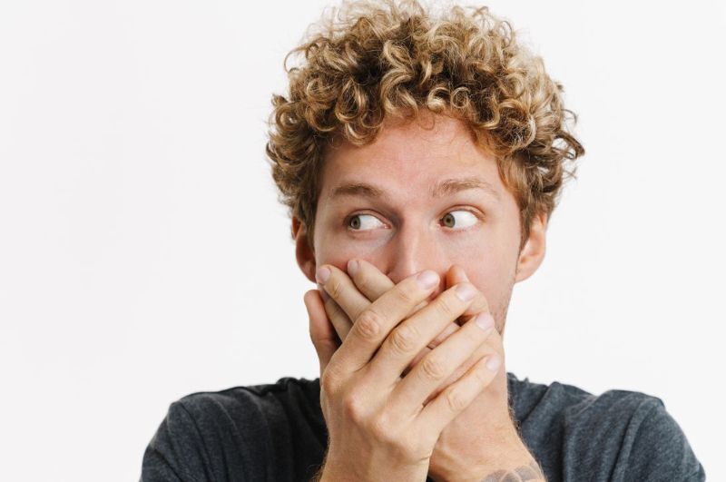 Man covering his mouth with his hand, expressing concern about adult thumb sucking habits.